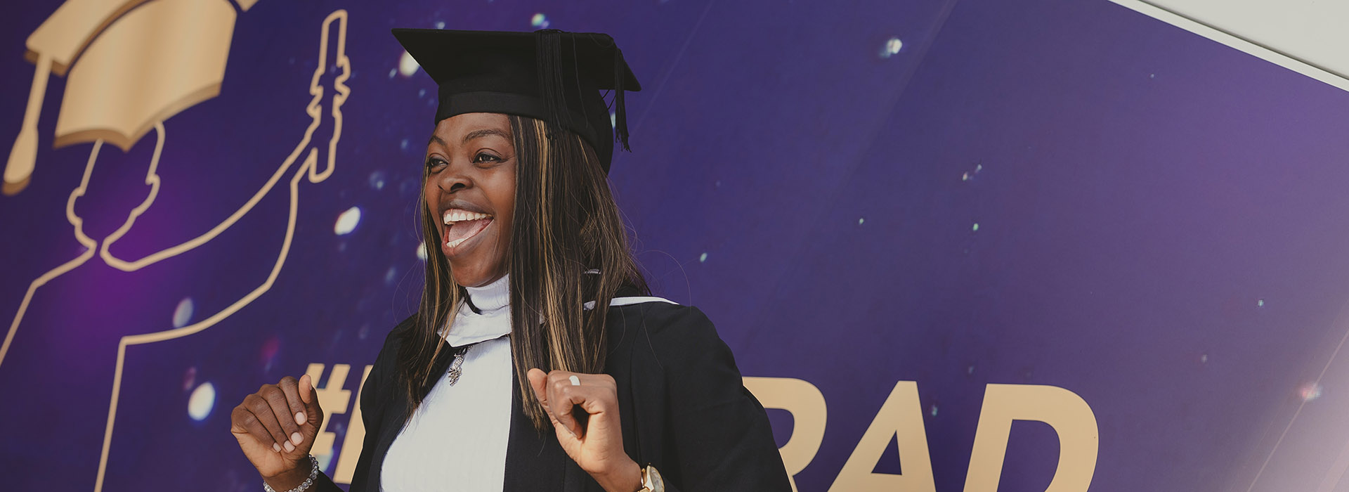 Graduate wearing a gown and cap, celebrating