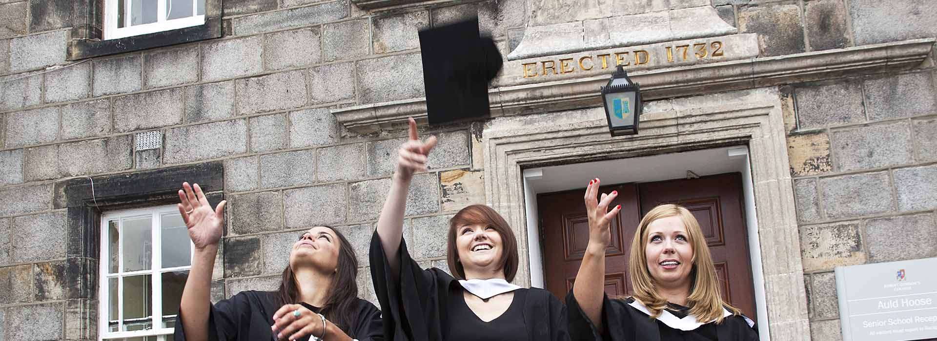 Graduates in gowns throwing their caps in the air