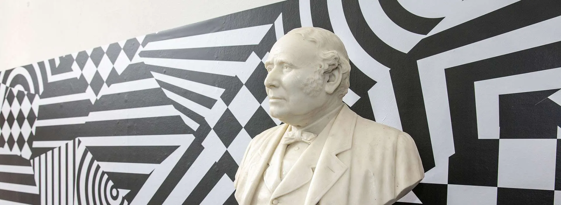 bust of John Gray in front of patterned background