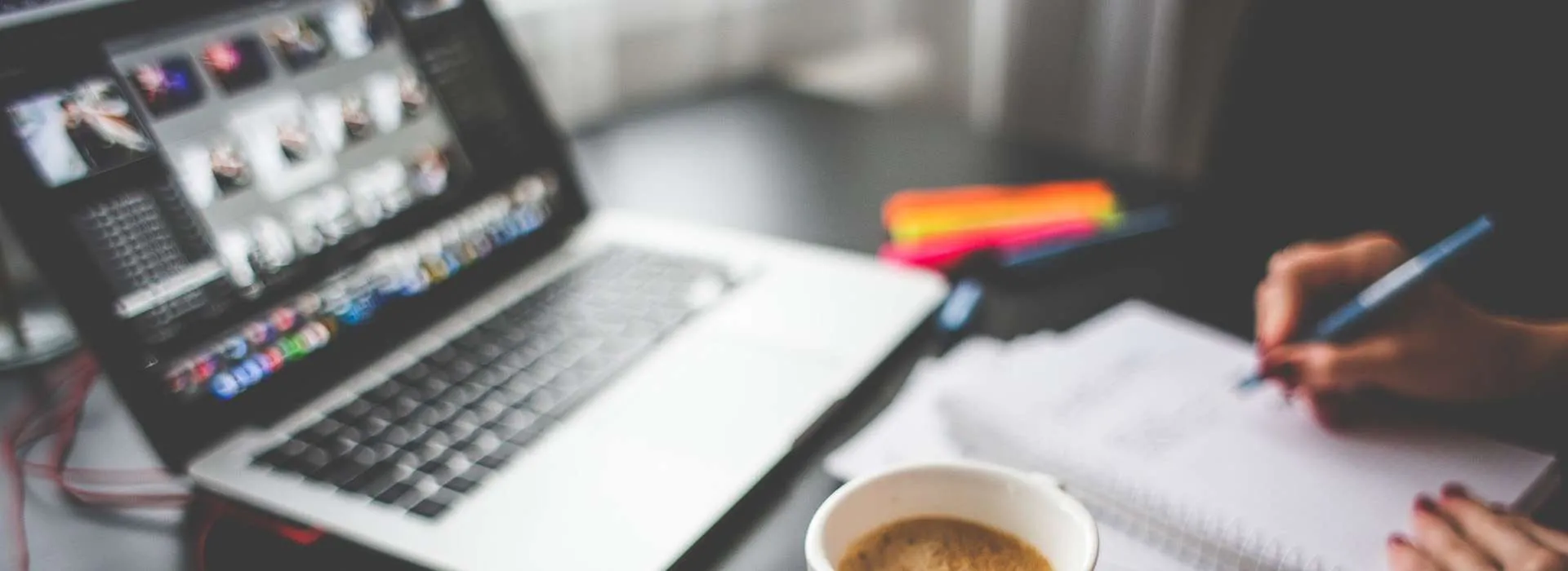 somebody taking notes next to their laptop and a coffee