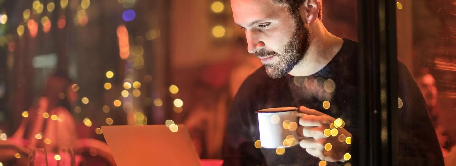 man in a cosy looking cafe holding a mug