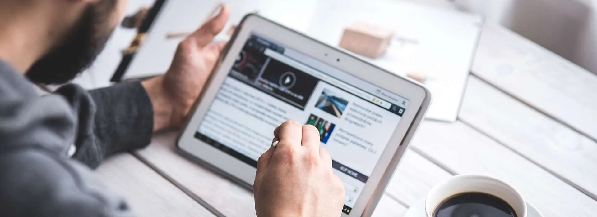 man using his ipad with a coffee sitting next to him