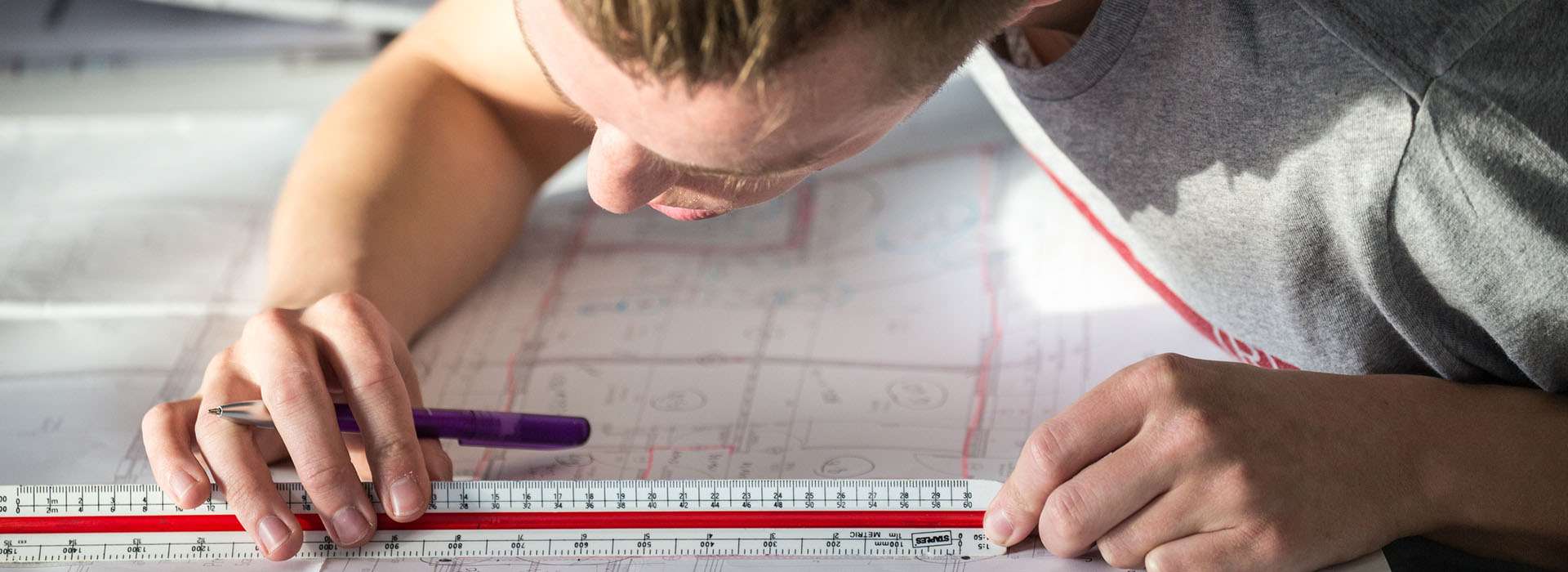 student taking measurement of a technical drawing