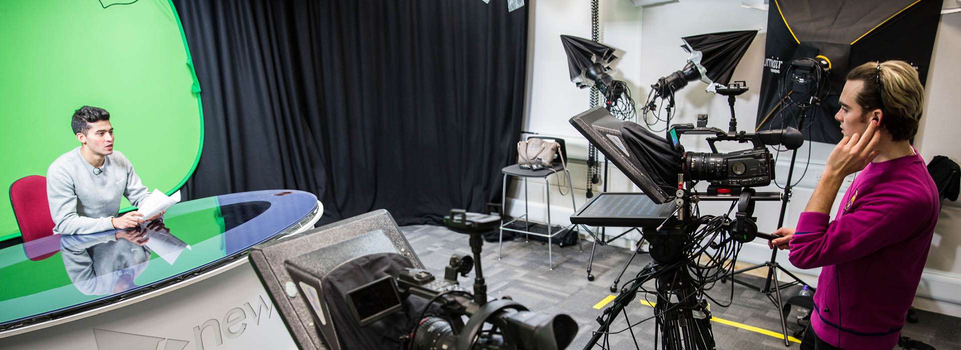 Students recording a news report in front of green screen in studio