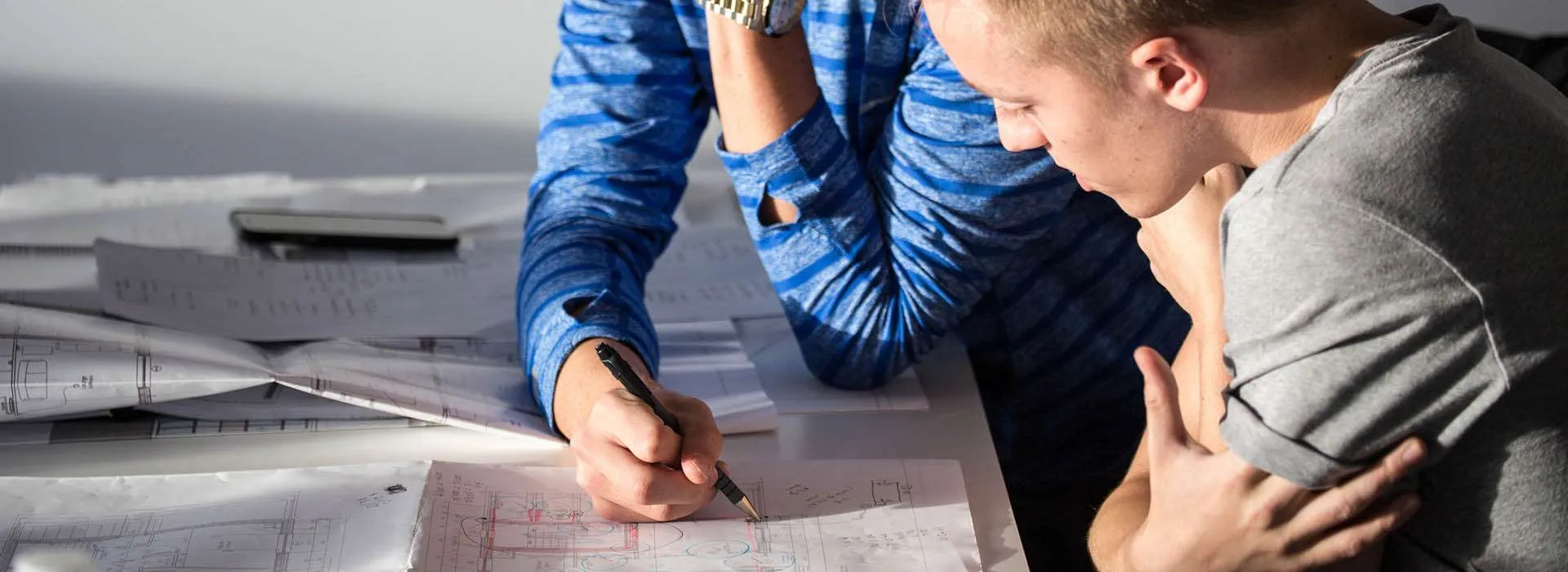 two men looking over technical drawings