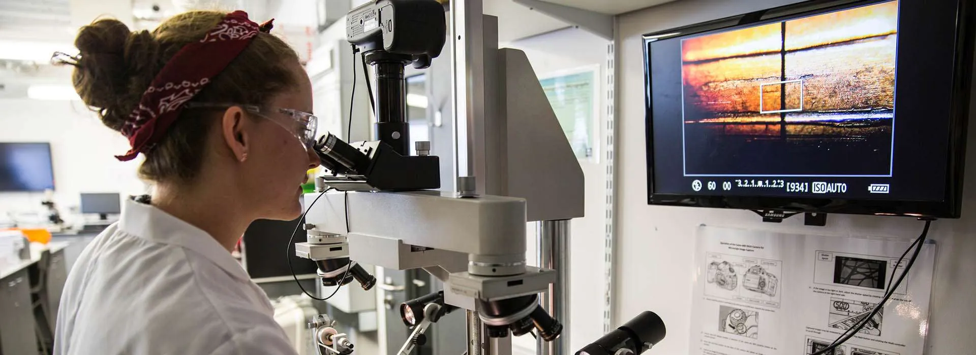 student looking through a large microscope