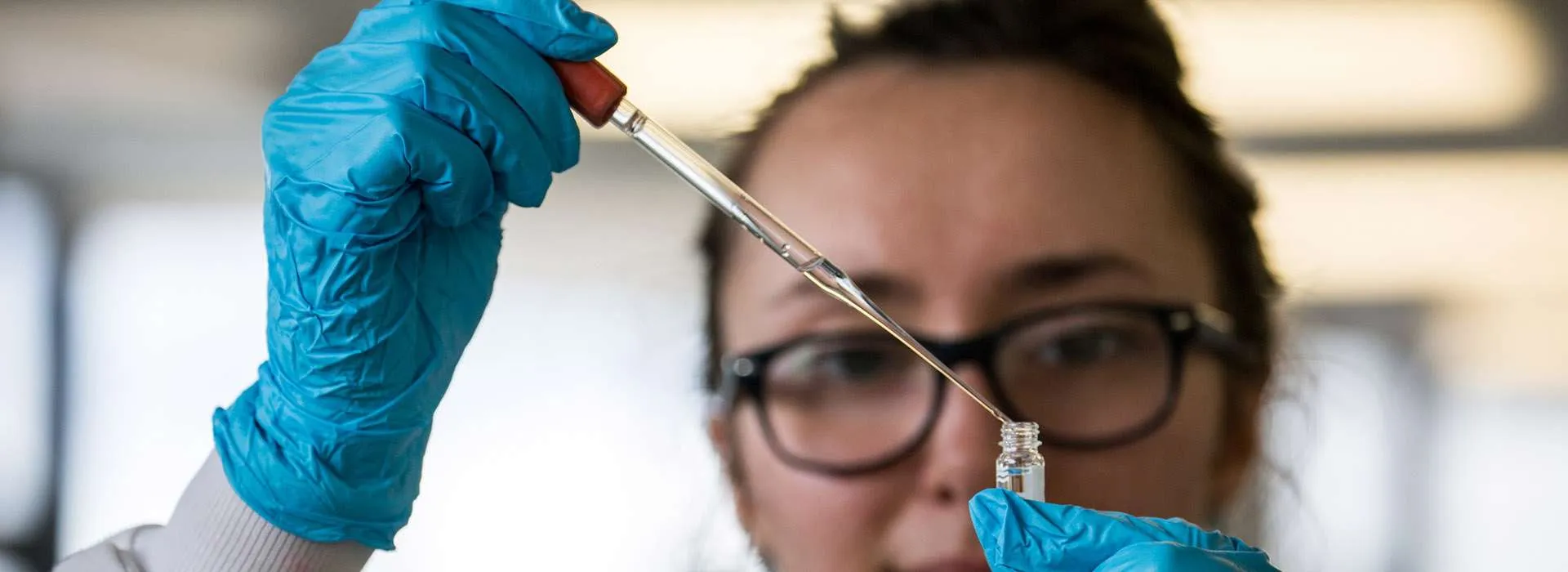 woman using a dropper to put liquid in a test tube