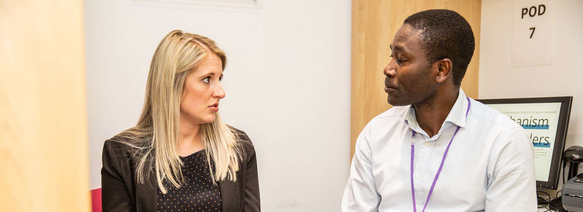 two people chatting holding books and a binder
