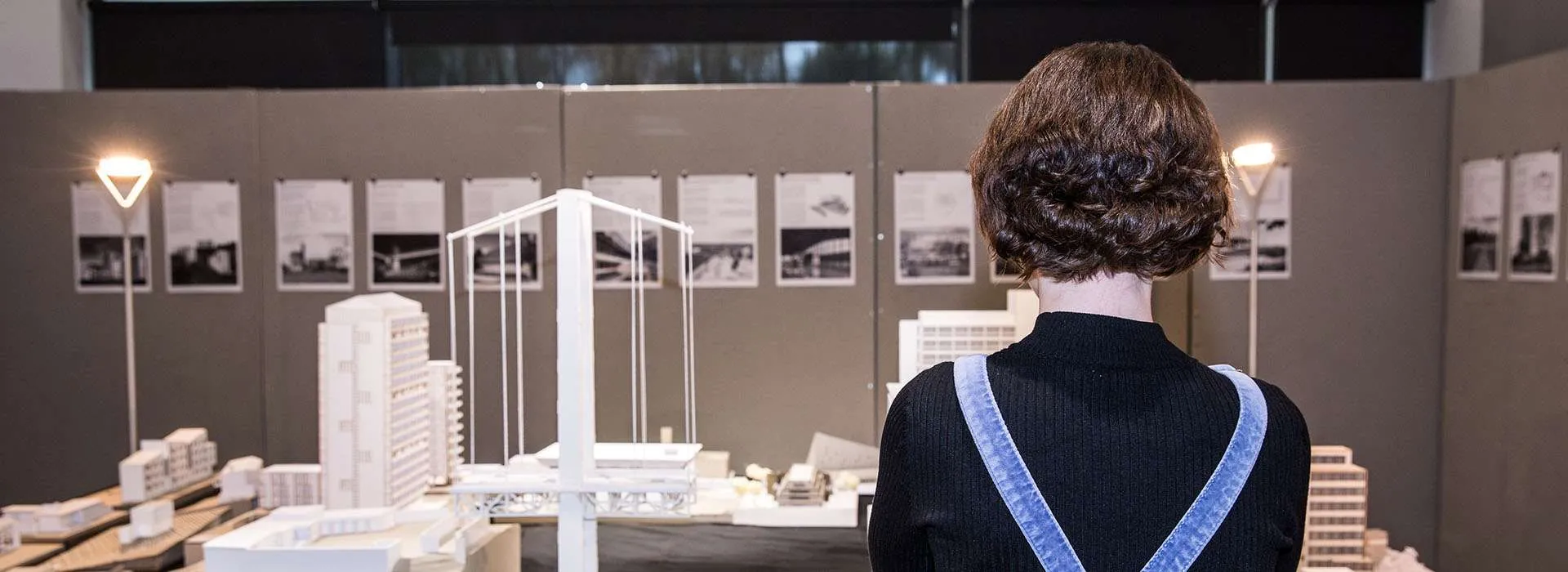 student standing in front of architectural models at a degree show