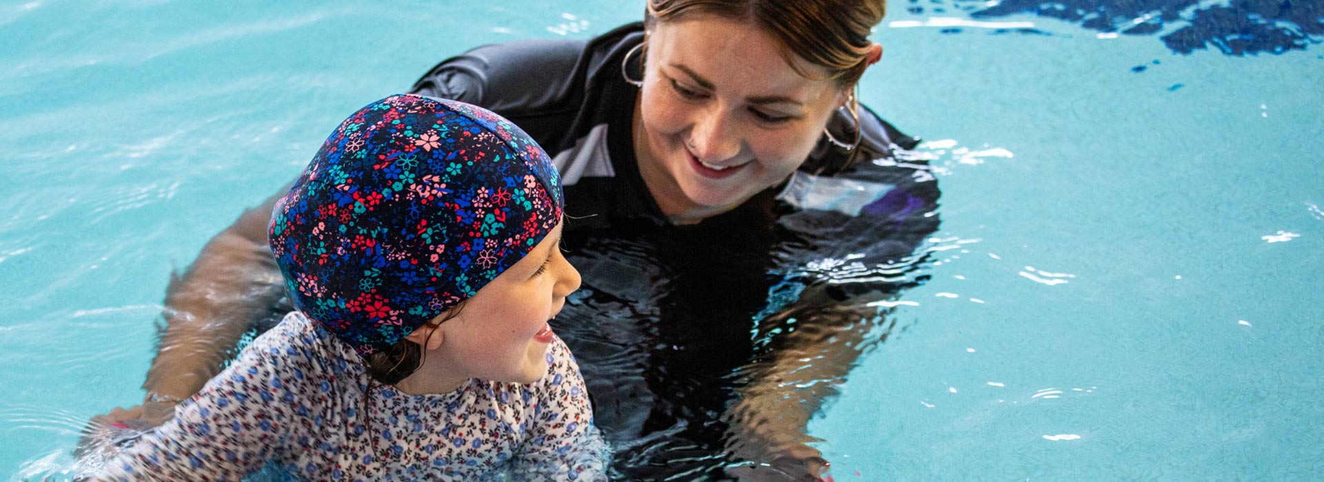 swimming instructor helping a child in the pool