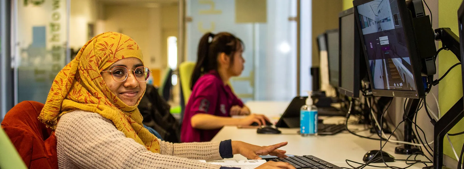 female student wearing a headscarf on a computer