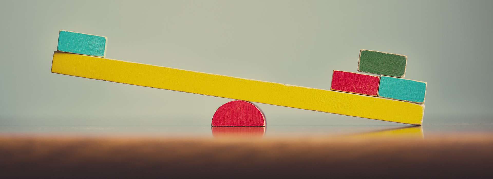 unequal coloured wooden blocks on a balance