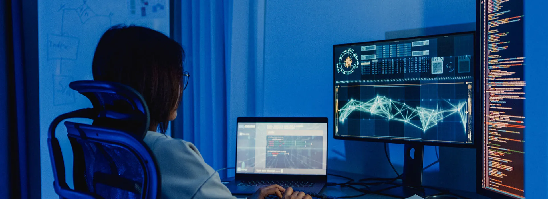 person coding on a desktop computer with multiple screens