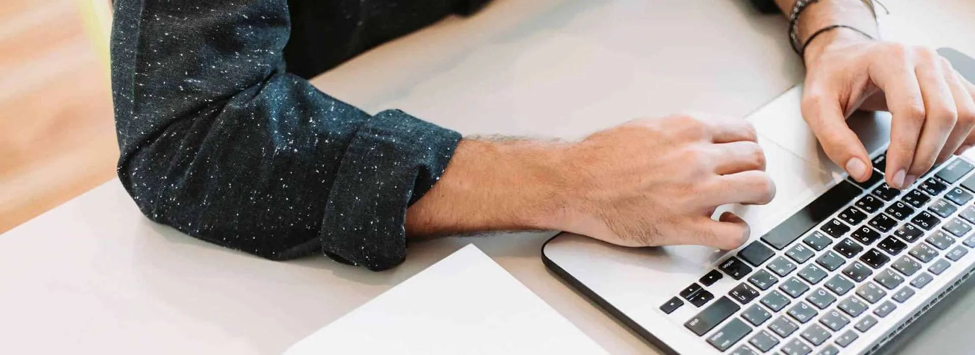 person sitting at a desk with a laptop and notebook