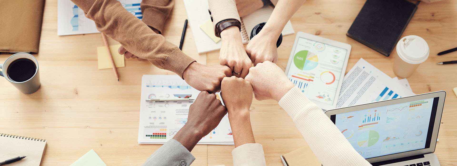 mixed race people fist bumping at a work table