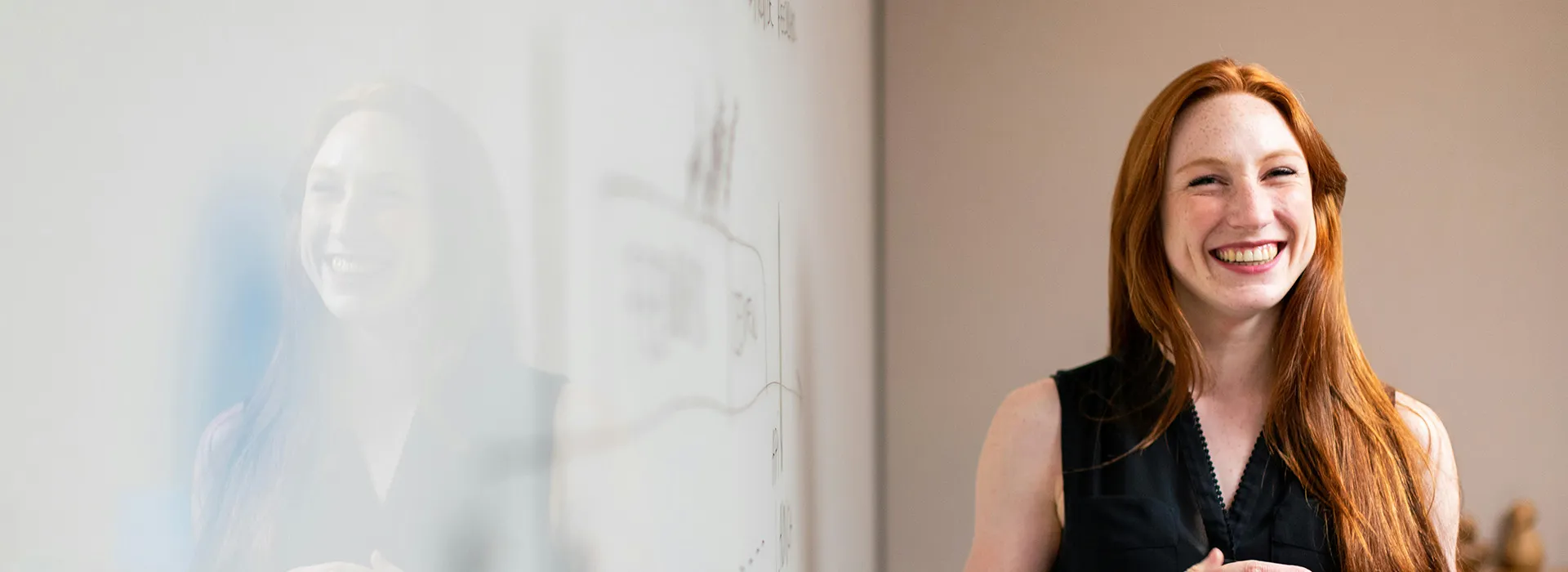 person grinning next to a white board