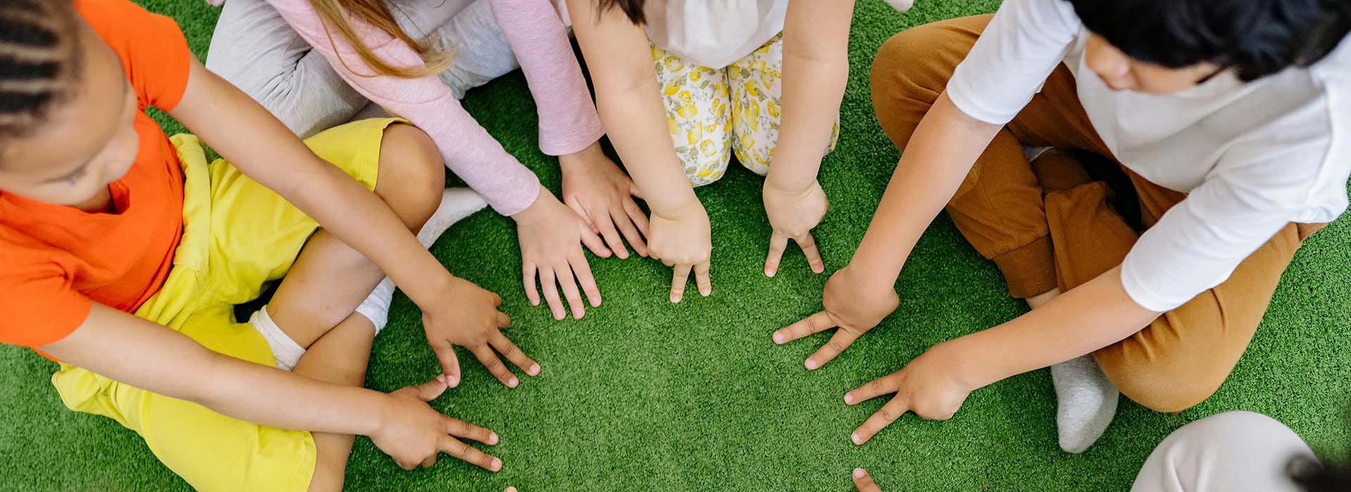 Children sitting in a circle with their hands together in the middle