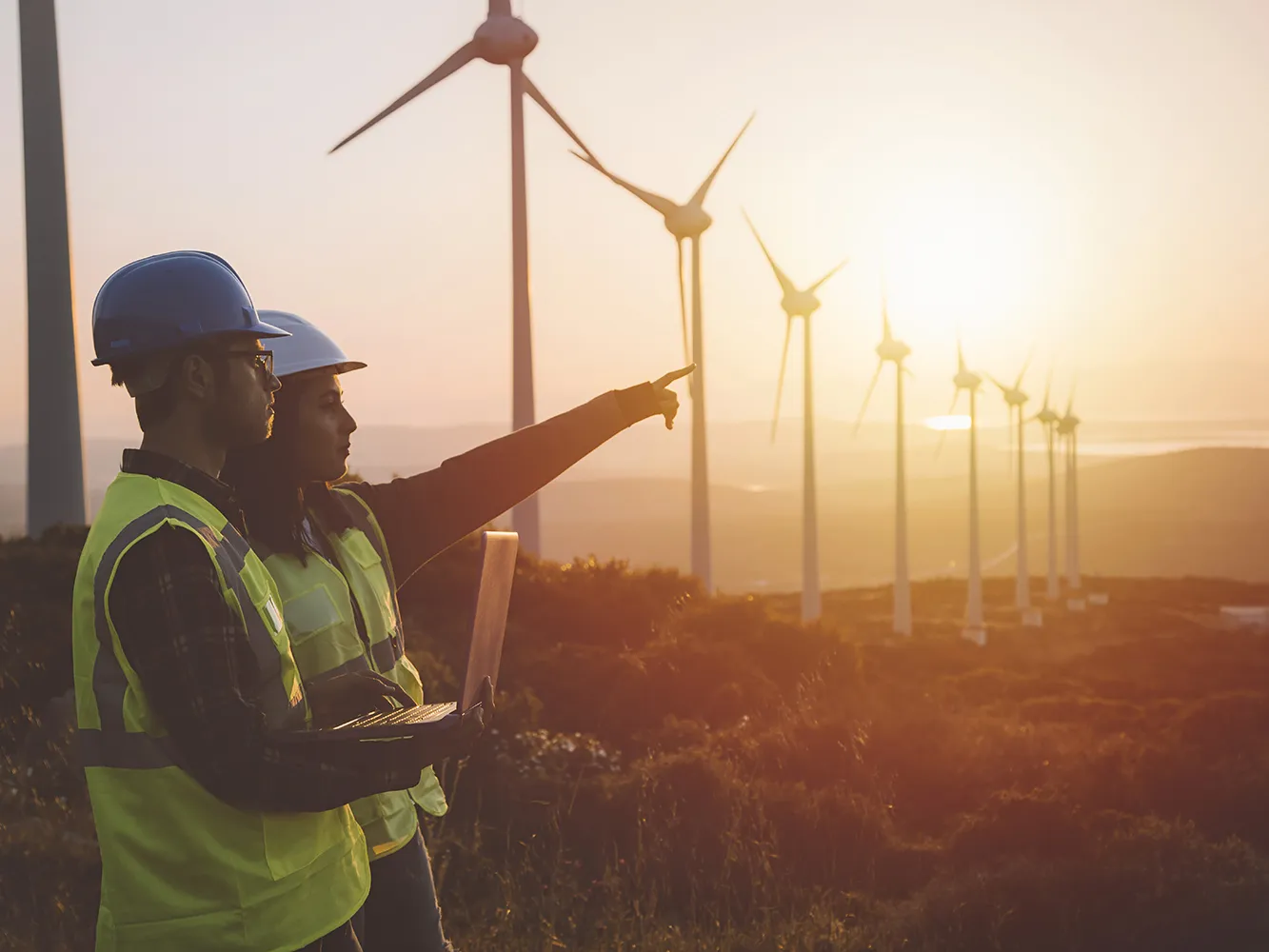 people in high vis looking at wind turbines