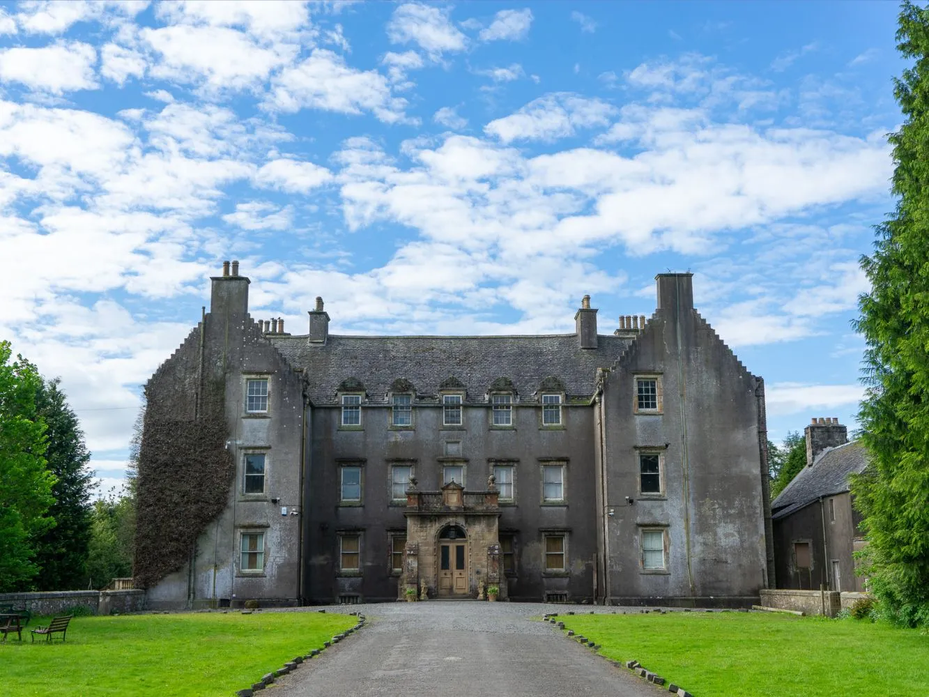 A mansion house with a lawn in front of it and blue skies above