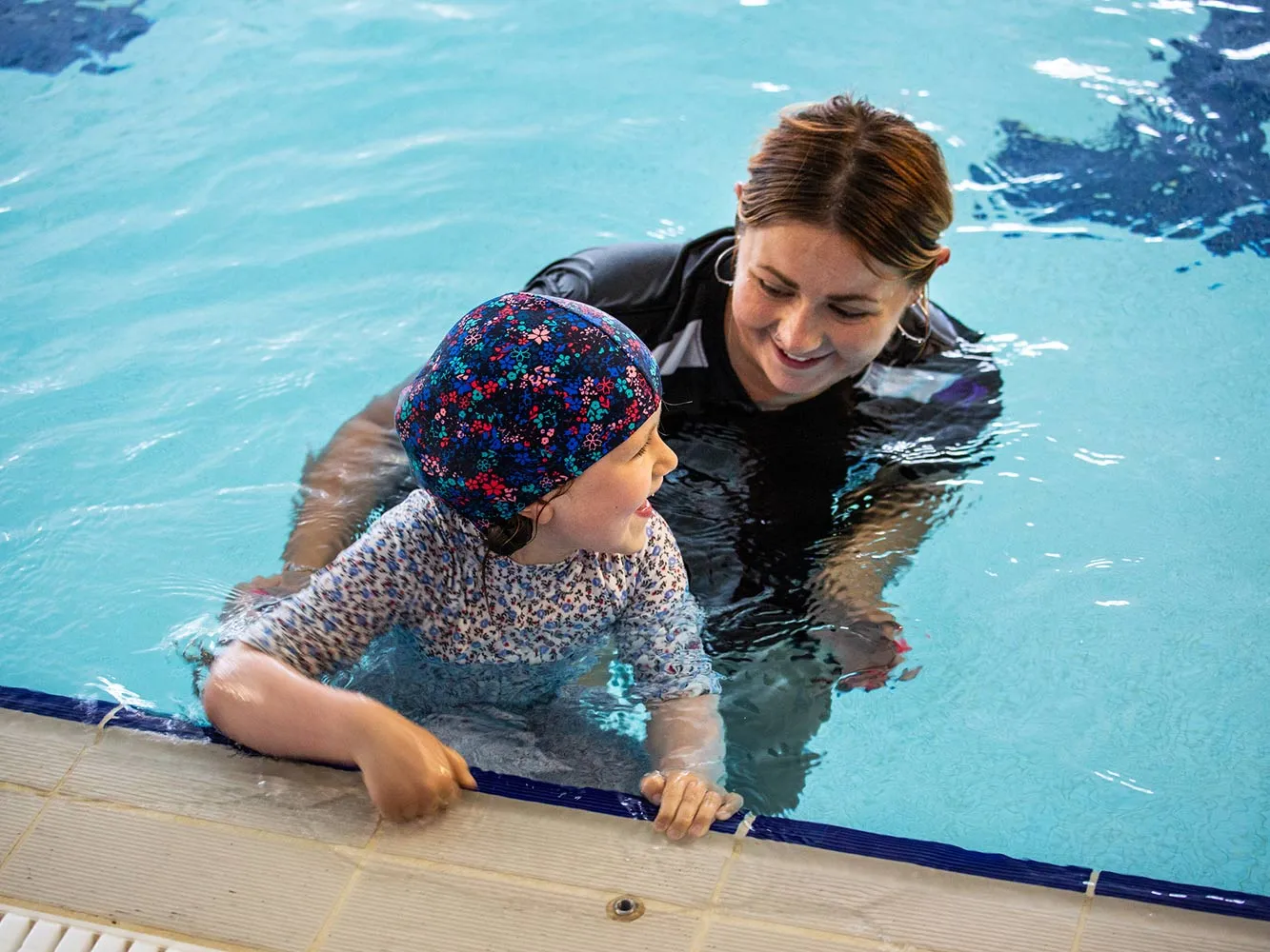 swimming instructor teaching a child in a pool