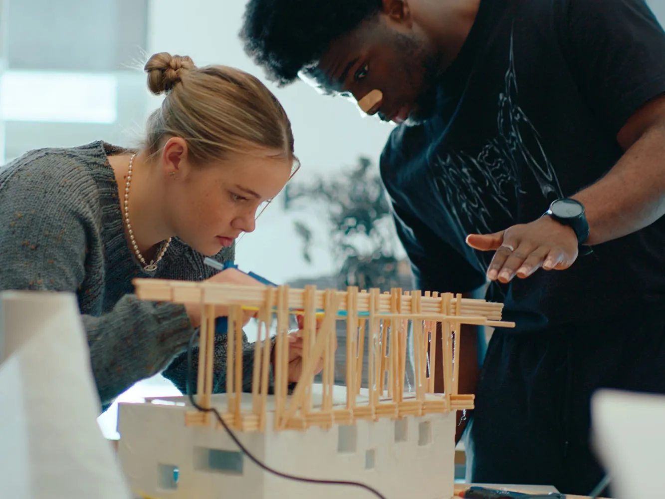 Two people looking at a wooden architecture model
