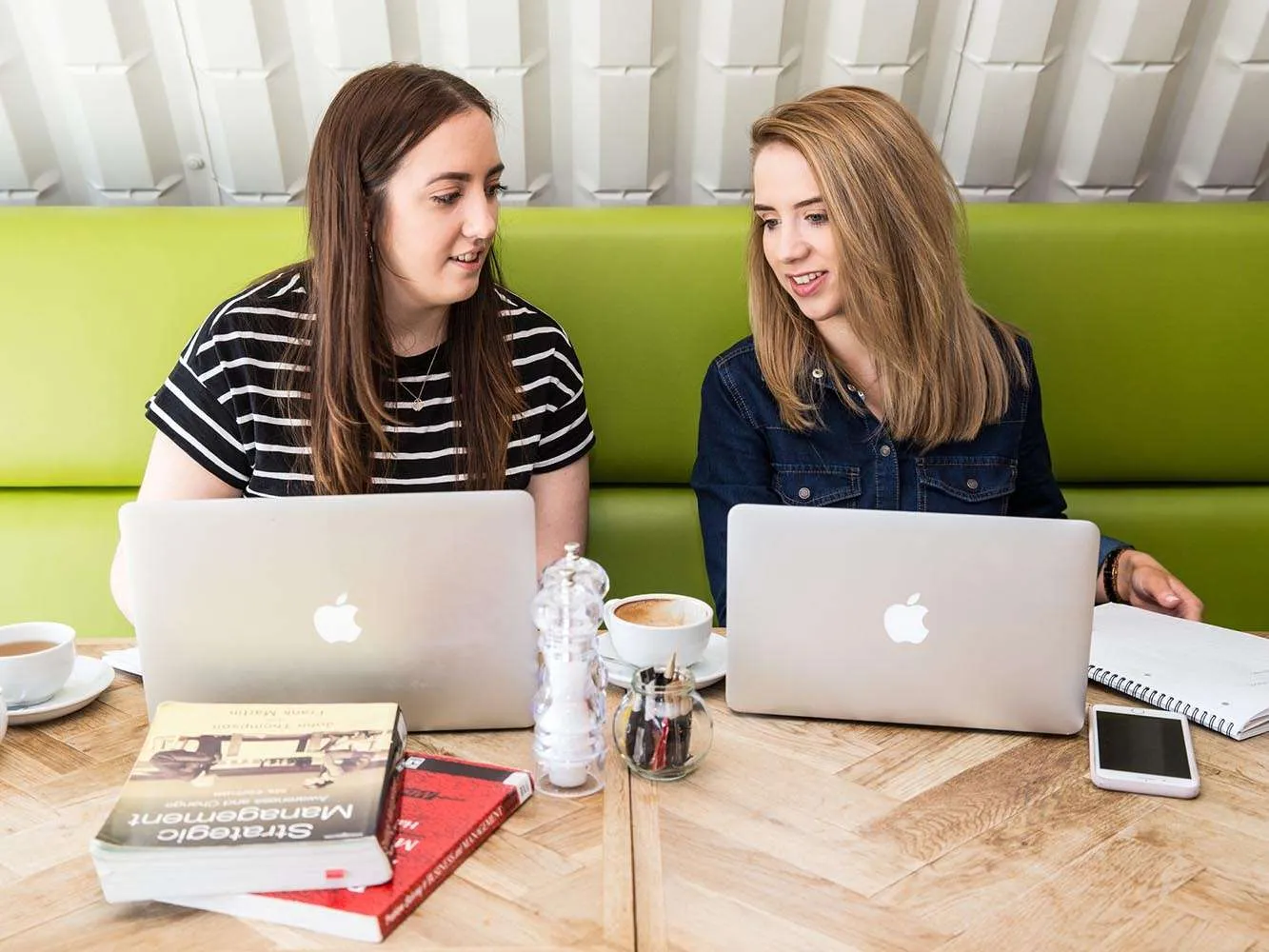 two students chatting with their laptops in front of them