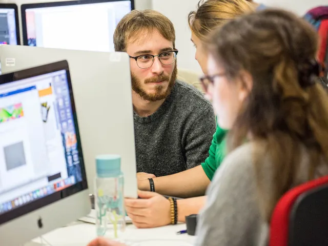 students chatting next to mac computers