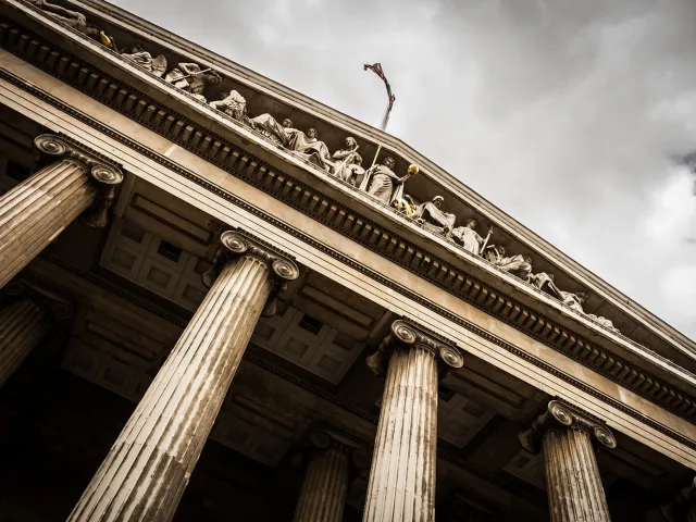 close up greek style building with pillars and fresco