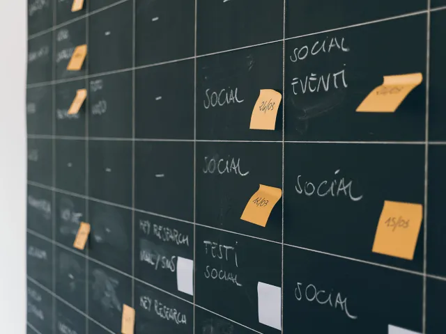 sticky notes on a blackboard with dates for a social media schedule