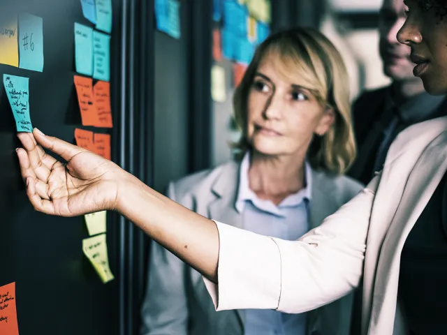 people placing sticky notes on a wall
