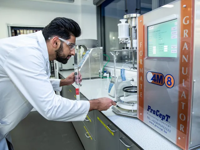 student in a lab coat looking at scientific equipment