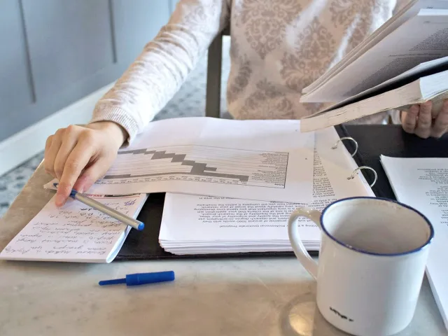 person holding pen over folder of documents
