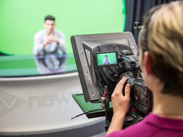 Person operating a TV camera in a green screen studio