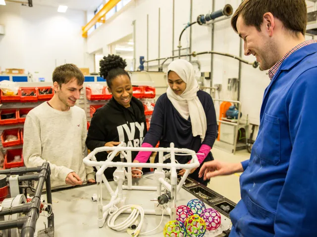 students standing next to ROV frame and 3D printed objects