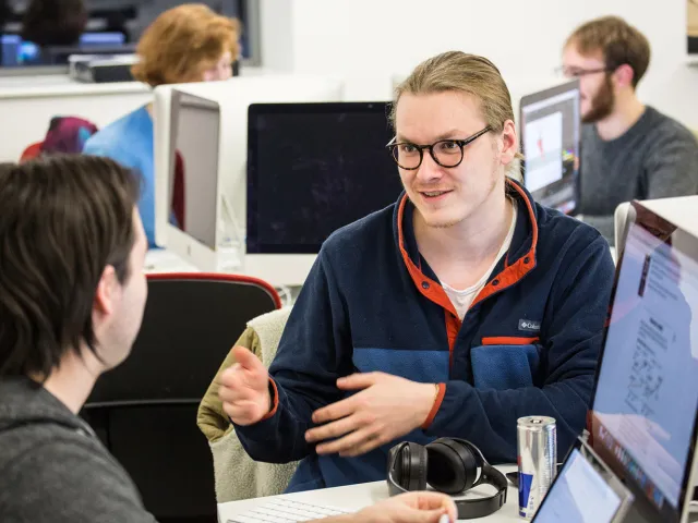 students chatting next to computers