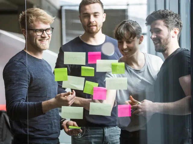 a group of people looking at post it notes on a glass wall