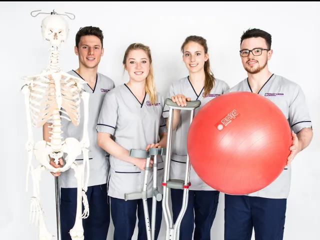 students wearing health uniforms next to a skeleton model