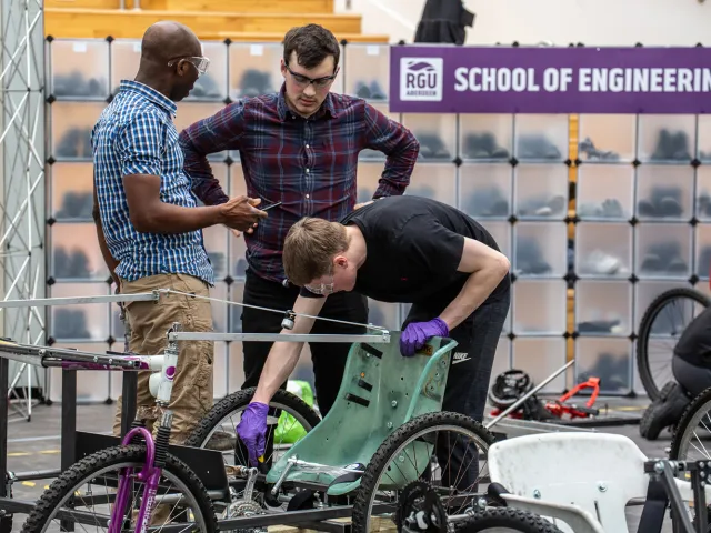 students working on vehicle with bicycle wheels
