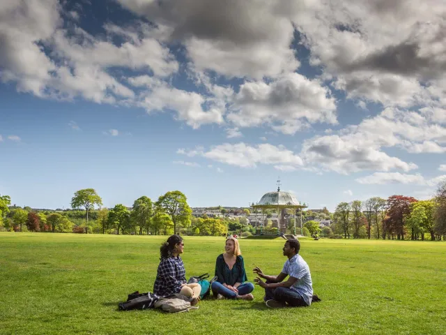 three people sitting in grass in Duthie Park Aberdeen