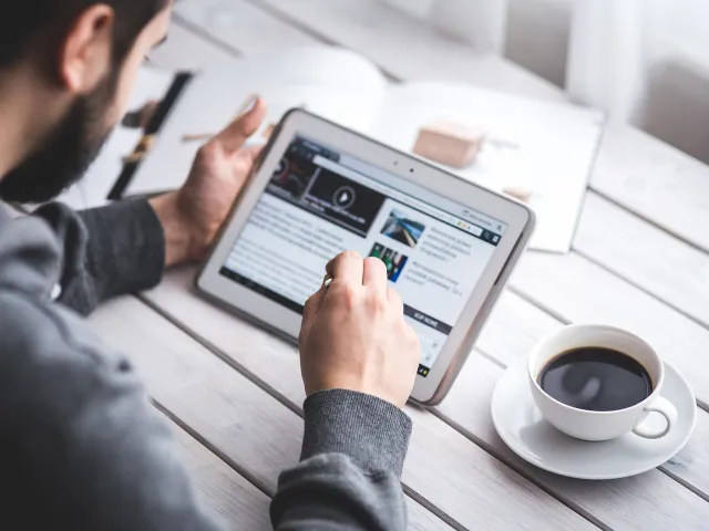 man using his ipad with a coffee sitting next to him
