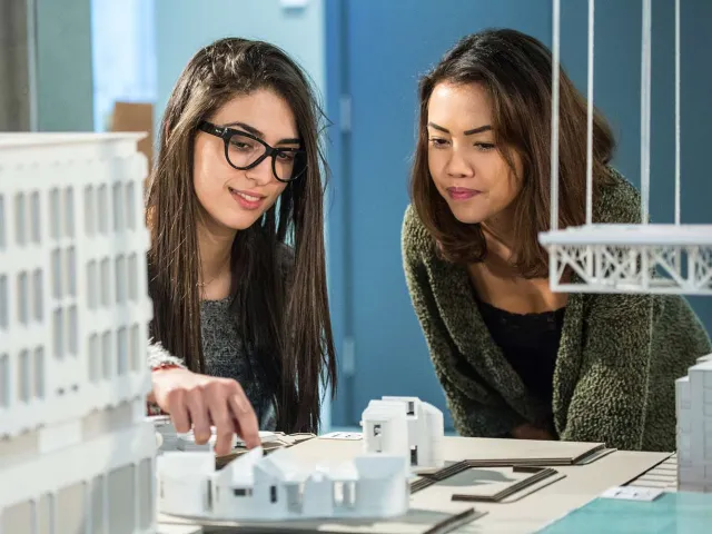 two students looking at architecture models