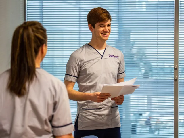 two students in health uniforms smiling
