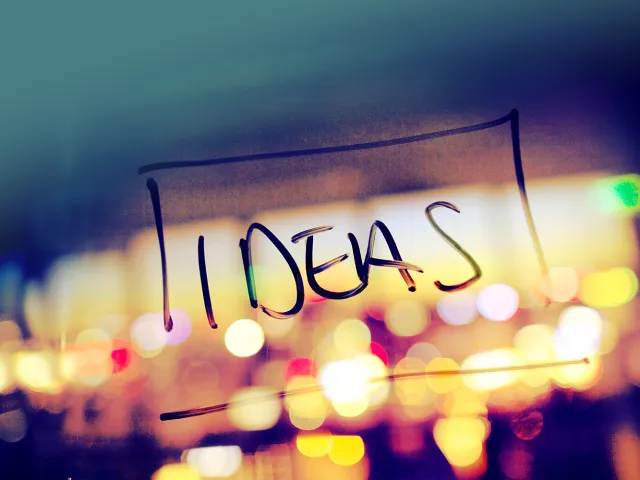 ideas written on glass in front of blurry lights