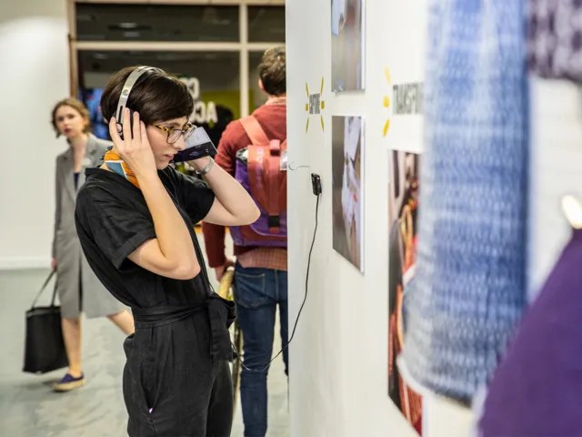 person interacting with an art display with headphones