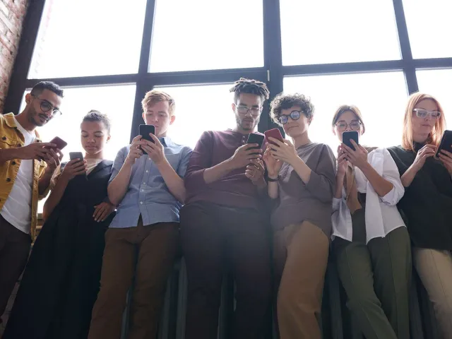 a group of young people all staring at their phones