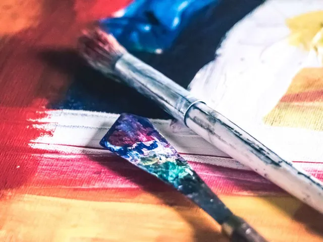 close up of paintbrush and tools on a painted canvas