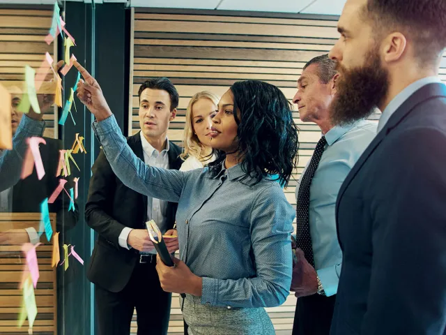 people looking at notes on a project board