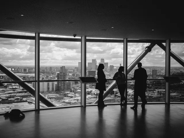 People standing by a window of a high rise building