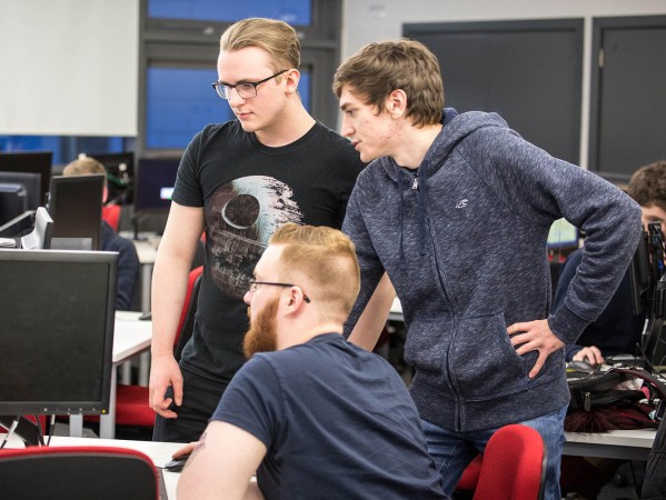 three students looking at a computer monitor together