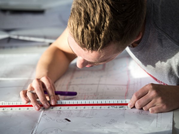 student taking measurement of a technical drawing